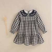 Imagen de Vestido de niña en cuadros bicolor beige tostado y negro con bordado en cuello