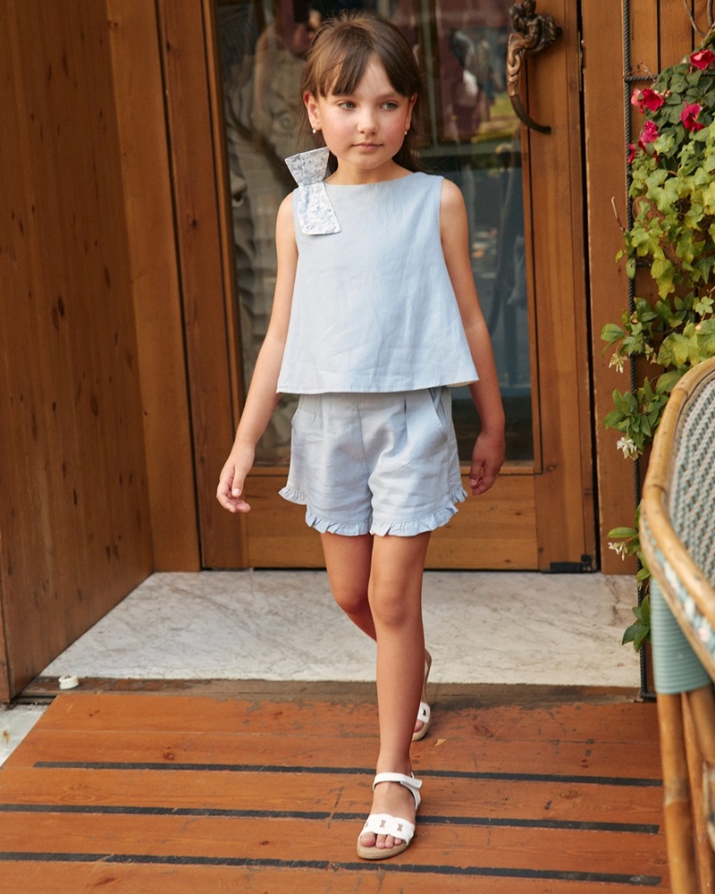 Imagen de Blusa de niña azul con lazo de flores y abertura trasera